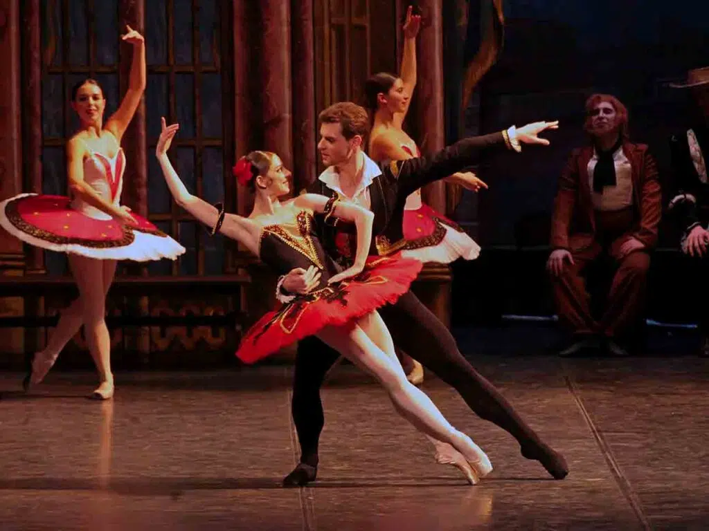 Ballerina in tutù rosso sostenuta dal partner durante un passo a due di Don Quixote