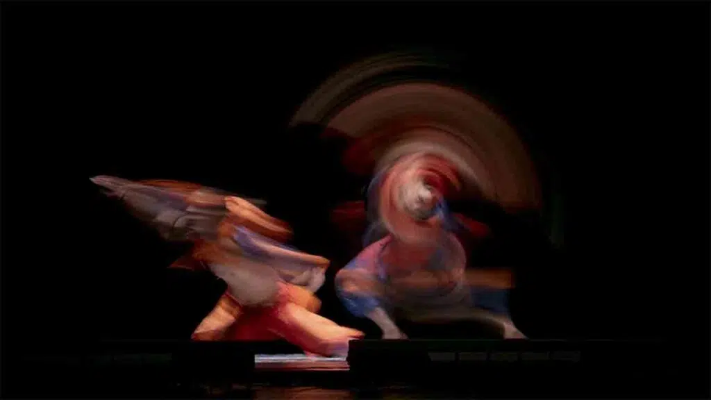 Performer in movimento con effetti di sfocatura rossi e blu su un palcoscenico buio