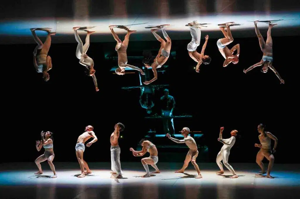 Danzatori dello Skopje Dance Theater si muovono davanti a una superficie riflettente in Trending Apocalypse